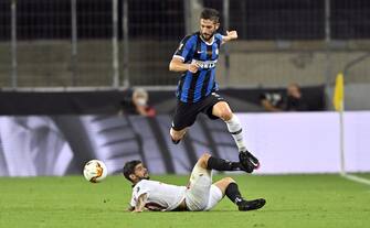 epa08617083 Roberto Gagliardini of Inter (up) in action against Ever Banega of Sevilla during the UEFA Europa League final match between Sevilla FC and Inter Milan in Cologne, Germany 21 August 2020.  EPA/Martin Meissner / POOL