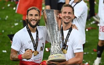epa08617469 Nemanja Gudelj (L) and Luuk de Jong of Sevilla pose with the trophy after winning the UEFA Europa League final match between Sevilla FC and Inter Milan in Cologne, Germany 21 August 2020.  EPA/Ina Fassbender / POOL