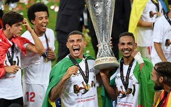epa08617419 Diego Carlos (L) and Fernando of Sevilla lift the trophy after winning the UEFA Europa League final match between Sevilla FC and Inter Milan in Cologne, Germany 21 August 2020.  EPA/Ina Fassbender / POOL