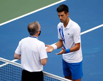 epa08651694 Novak Djokovic of Serbia (R) talks to Head of Officiating at International Tennis Federation (ITF) Soeren Friemel  after he accidentally hit a linesperson with a ball in the throat during his match against Pablo Carreno Busta of Spain on the seventh day of the US Open Tennis Championships at the USTA National Tennis Center in Flushing Meadows, New York, USA, 06 September 2020. Djokovic was defaulted from tournament. Due to the coronavirus pandemic, the US Open is being played without fans and runs from 31 August through 13 September.  EPA/JASON SZENES