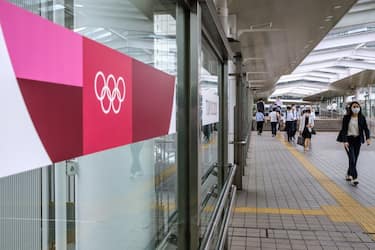 This picture taken on July 15, 2020 shows a Tokyo 2020 Olympic Games banner (L) pictured as people walk past on a footbridge outside a railway station in Tokyo. - Due to the COVID-19 coronavirus pandemic, the International Olympic Committee (IOC) was forced to delay the Games until July 23, 2021 -- the first peacetime postponement in history. But with one year to go, many questions remain unanswered, with surveys suggesting Tokyo residents are beginning to cool on the idea of hosting the Games during a global pandemic. (Photo by Philip FONG / AFP) / TO GO WITH AFP SERIES ONE YEAR TO GO AHEAD OF THE SUMMER OLYMPIC GAMES (Photo by PHILIP FONG/AFP via Getty Images)