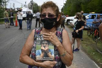 A woman holding a book on Argentine football star Diego Maradona mourns outside the gated community where his home is located, in Benavidez, Buenos Aires province, where he died on November 25, 2020. (Photo by JUAN MABROMATA / AFP) (Photo by JUAN MABROMATA/AFP via Getty Images)