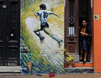 A man looks at flowers left next to a mural depicting Argentine football star Diego Maradona, in San Telmo neighborhood, Buenos Aires on November 25, 2020, on the day of his death. (Photo by ALEJANDRO PAGNI / AFP) (Photo by ALEJANDRO PAGNI/AFP via Getty Images)