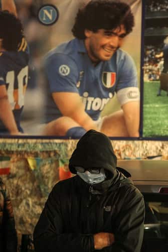 A man wearing a face mask stands at the so-called "Maradona Corner" at the top of the Quartieri Spagnoli in Naples on November 25, 2020 as people gather there to mourn after the annoucement's of Argentinian football legend Diego Maradona's death. - Argentine football legend Diego Maradona has died at the age of 60, his spokesman announced November 25, 2020. (Photo by Carlo Hermann / AFP) (Photo by CARLO HERMANN/AFP via Getty Images)