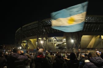 People gather at the main entrance of the San Paolo stadium in Naples on November 25, 2020 in front of an image of Argentinian football legend Diego Maradona reading "The King", to mourn after the annoucement's of Maradona's death. - Argentine football legend Diego Maradona has died at the age of 60, his spokesman announced November 25, 2020. (Photo by CARLO HERMANN / AFP) (Photo by CARLO HERMANN/AFP via Getty Images)