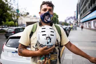 BUENOS AIRES, ARGENTINA - NOVEMBER 25: A fan shows his helmet with a sticker of Maradona and wears a face mask with the face of the soccer legend after the news of the death of Diego Maradona was known on November 25, 2020 in Buenos Aires, Argentina. Argentine soccer legend Diego Armando Maradona died today aged 60. (Photo by Tomas Cuesta/Getty Images)
