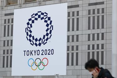 (200330) -- TOKYO, March 30, 2020 (Xinhua) -- A man wearing protective face masks walk past the logo of the Tokyo 2020 Olympic Games displayed on a wall of The Tokyo Metropolitan Government Building in Tokyo, Japan, March 25, 2020. The Tokyo Olympic Games has been rescheduled to July 23 to August 8, 2021, organizers of the Tokyo 2020 Olympic and Paralympic Games announced on Monday. (Xinhua/Du Xiaoyi) - Du Xiaoyi -//CHINENOUVELLE_1822028/2003301834/Credit:CHINE NOUVELLE/SIPA/2003301838 (Tokyo - 2020-03-25, CHINE NOUVELLE/SIPA / IPA) p.s. la foto e' utilizzabile nel rispetto del contesto in cui e' stata scattata, e senza intento diffamatorio del decoro delle persone rappresentate