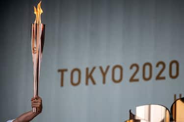 TOPSHOT - A torchbearer holds an Olympic torch during the lighting ceremony of the Olympic flame at Machida Shibahiro, on the first day of the torch relay in Tokyo on July 9, 2021. (Photo by Philip FONG / AFP) (Photo by PHILIP FONG/AFP via Getty Images)