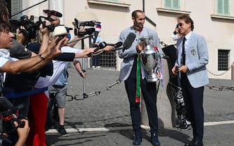 1233942097 Italy's coach Roberto Mancini (R) and Italy's defender Giorgio Chiellini, carrying the UEFA EURO 2020 trophy, address the media as players and staff of Italy's national football team arrive to attend a ceremony at the Quirinale presidential palace in Rome on July 12, 2021, a day after Italy won the UEFA EURO 2020 final football match between Italy and England. (Photo by Vincenzo PINTO / AFP) (Photo by VINCENZO PINTO/AFP via Getty Images)