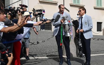 Italy's coach Roberto Mancini (R) and Italy's defender Giorgio Chiellini, carrying the UEFA EURO 2020 trophy, address the media as players and staff of Italy's national football team arrive to attend a ceremony at the Quirinale presidential palace in Rome on July 12, 2021, a day after Italy won the UEFA EURO 2020 final football match between Italy and England. (Photo by Vincenzo PINTO / AFP) (Photo by VINCENZO PINTO/AFP via Getty Images)