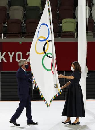 epa09406066 IOC president Thomas Bach (L) hands over the Olympic flag to Paris Mayor Anne Hidalgo during the Closing Ceremony of the Tokyo 2020 Olympic Games at the Olympic Stadium in Tokyo, Japan, 08 August 2021. Paris will host the 2024 Olympic Games.  EPA/MICHAEL REYNOLDS