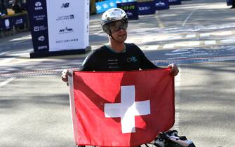 epa09569959 Marcel Hug of Switzerland holds up his flag after winning  the menÕs wheelchair  division of the 2021 TCS New York City Marathon in New York, New York, USA, 07 November 2021.  EPA/Peter Foley