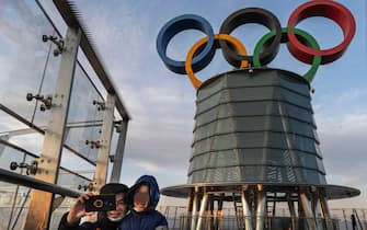 BEIJING, CHINA - DECEMBER 11: Visitors pose for photos near a column with the Olympic Rings as they visit the top level of the Olympic Tower in the Olympic Green near the National Stadium, also known as the Bird's Nest, on December 11, 2021 in Beijing, China. The area will host a number of events for the Beijing 2022 Winter Olympic Games, including the opening ceremonies, which is set to open on February 4, 2022. (Photo by Kevin Frayer/Getty Images)