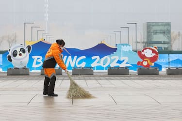 BEIJING, CHINA - JANUARY 23:  A staff member sweeps a street in front of a Beijing 2022 Winter Olympics sculpture on January 23, 2022 in Beijing, China. The Beijing 2022 Winter Olympics are set to open February 4th.  (Photo by Lintao Zhang/Getty Images)