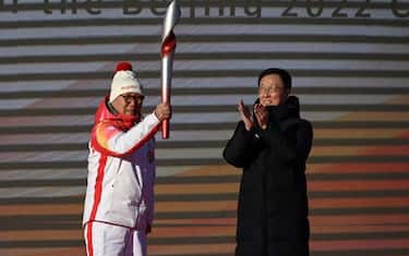 Luo Zhihuan (L), China's first world speed skating champion, holds the Olympic Torch after China's Vice Premier Han Zheng (R) passes the torch during the torch launch ceremony at Olympic Forest Park on the first day of the torch relay in Beijing on February 2, 2022, just two days before the start of the Beijing 2022 Winter Olympic Games. (Photo by Leo RAMIREZ / AFP) (Photo by LEO RAMIREZ/AFP via Getty Images)