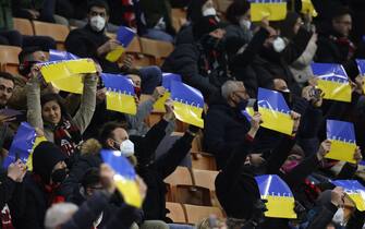 MILAN, ITALY - MARCH 01: Fans hold up cards bearing the word 'peace' on a background of yellow and blue to represent the Ukraine national flag during the Coppa Italia Semi Final 1st Leg match between AC Milan and FC Internazionale at Stadio Giuseppe Meazza on March 01, 2022 in Milan, Italy. (Photo by Jonathan Moscrop/Getty Images)