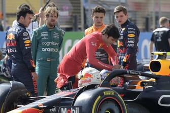 Ferrari's Spanish driver Carlos Sainz Jr (C) inspects the cockpit of Red Bull's Mexican driver Sergio Perez (L) as Aston Martin's German driver Sebastian Vettel (2nd-L), McLaren's British driver Lando Norris, and Red Bull's Dutch driver Max Verstappen (R) look on during the first day of Formula One (F1) pre-season testing at the Bahrain International Circuit in the city of Sakhir on March 12, 2021. (Photo by Mazen MAHDI / AFP) (Photo by MAZEN MAHDI/AFP via Getty Images)