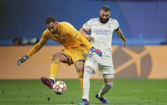 MADRID, SPAIN - MARCH 09: Karim Benzema (R) of Real Madrid CF tackles goalkeeper Gianluigi Donnarumma (L) of Paris Saint-Germain during the UEFA Champions League Round Of Sixteen Leg Two match between Real Madrid and Paris Saint-Germain at Estadio Santiago Bernabeu on March 09, 2022 in Madrid, Spain. (Photo by Gonzalo Arroyo Moreno/Getty Images)