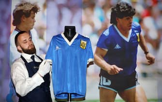 A Sotheby's technician adjusts a football shirt worn by Argentina's Diego Maradona during the 1986 World Cup quarter-final match against England, during a photocall at Sotheby's auction house in London on April 20, 2022, ahead of its sale. - The jersey worn by Diego Maradona when he scored twice against England in the 1986 World Cup, including the infamous "hand of God" goal, is to be auctioned off this month, Sotheby's announced Wednesday. The blue number 10 shirt has been owned since the end of the controversial World Cup encounter by opposing midfielder Steve Hodge, who swapped his jersey with Maradona after England lost 2-1. (Photo by ADRIAN DENNIS / AFP) (Photo by ADRIAN DENNIS/AFP via Getty Images)