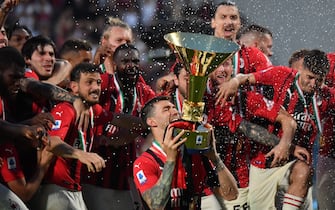 AC Milan's Italian defender Alessio Romagnoli bites the cup as AC Milan's players celebrate with the winner's trophy after AC Milan won the Italian Serie A football match between Sassuolo and AC Milan, securing the "Scudetto" championship on May 22, 2022 at the Mapei - Citta del Tricolore stadium in Sassuolo. (Photo by Tiziana FABI / AFP) (Photo by TIZIANA FABI/AFP via Getty Images)