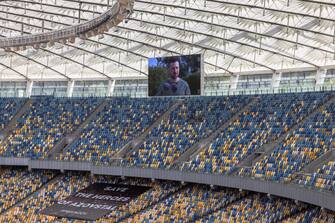 epa10134448 Ukrainian President Volodymyr Zelensky is seen on a screen delivering a speech, before the opening soccer match of the new season of Ukrainian Premier League between Shakhtar Donetsk and Metalist 1925 Kharkiv at the empty Olimpiyskiy stadium, in Kyiv, Ukraine, 23 August 2022. Ukrainian football Premier League began its new season on 23 August with out fans amid fears of bombs annd missiles alerts, a day before six months of the Russian invasion are marked. Russian troops on 24 February 2022 entered Ukrainian territory, starting a conflict that provoked destruction and a humanitarian crisis.  EPA/ROMAN PILIPEY