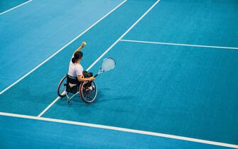 High angle view of a teenage girl playing and practicing wheelchair tennis at an indoor tennis court