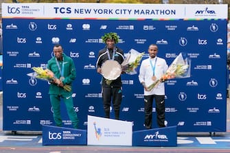 epa10290926 Men s first place winner Evans Chebet (C) of Kenya with his trophy on the medals podium after winning the New York City marathon in New York, New York, USA, 06 November 2022. Also pictured are second place finisher Shura Kitata (L) of Ethiopia and third place finisher Abdi Nageeye (R) of the Netherlands.  EPA/JUSTIN LANE