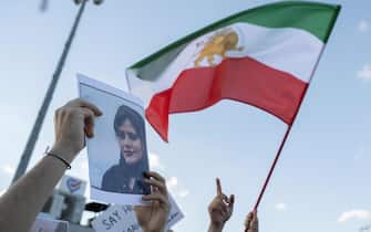 A protestors holds a photo of Kurdish Iranian woman Mahsa Amini as another waves Iran's former flag during a demonstration against the Iranian regime and in support of Iranian women, after Amini died after being arrested in Tehran by the Islamic Republic's morality police, in Istanbul on October 2, 2022. - Hundreds of protesters took to the streets in Turkey on October 2 to condemn Iran's crackdown on women-led demonstrations, in which least 92 people have been killed, sparked by a young woman's death after her arrest by the country's notorious morality police. Kurdish Iranian Amini, 22, was pronounced dead on September 16 after she was detained for allegedly breaching rules requiring women to wear hijab headscarves and modest clothes, sparking Iran's biggest wave of popular unrest in almost three years. (Photo by Bulent KILIC / AFP) (Photo by BULENT KILIC/AFP via Getty Images)