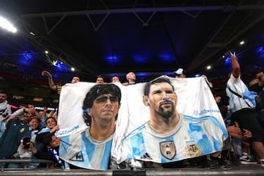 LONDON, ENGLAND - JUNE 01: A fan holds a banner with the faces of Diego Maradona and Lionel Messi during the 2022 Finalissima match between Italy and Argentina at Wembley Stadium on June 01, 2022 in London, England.Photo by Alex Pantling/Getty Images)