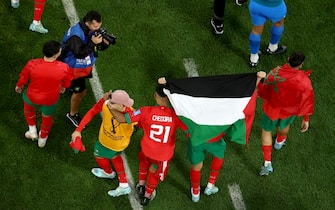 DOHA, QATAR - DECEMBER 10: Morocco players hold up a flag in support of Palestine as they celebrate their 1-0 victory in the FIFA World Cup Qatar 2022 quarter final match between Morocco and Portugal at Al Thumama Stadium on December 10, 2022 in Doha, Qatar. (Photo by Lars Baron/Getty Images)