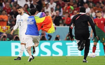 epa10335266 A pitch invader wearing a 'Respect for Iranian women' tshirt and holding a rainbow flag runs from the stadium security during the FIFA World Cup 2022 group H soccer match between Portugal and Uruguay at Lusail Stadium in Lusail, Qatar, 28 November 2022.  EPA/Mohamed Messara