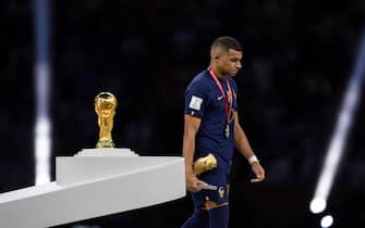 LUSAIL CITY, QATAR - DECEMBER 18: Kylian Mbappe of France walks past the FIFA World Cup trophy after winning the Golden Boot award following the FIFA World Cup Qatar 2022 Final match between Argentina and France at Lusail Stadium on December 18, 2022 in Lusail City, Qatar. (Photo by Simon Bruty/Anychance/Getty Images)