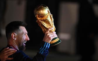 Argentina's captain and forward Lionel Messi holds the FIFA World Cup Trophy upon arrival at Ezeiza International Airport after winning the Qatar 2022 World Cup tournament in Ezeiza, Buenos Aires province, Argentina on December 20, 2022. (Photo by Luis ROBAYO / AFP) (Photo by LUIS ROBAYO/AFP via Getty Images)