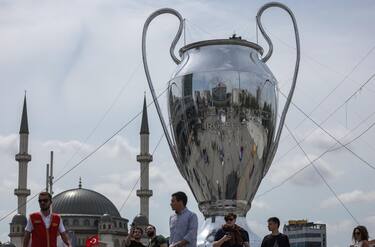 epa10679818 People walk around a huge model of the UEFA Champions League trophy backdropped by the Taksim Mosque at the Taksim Square in Istanbul, Turkey, 08 June 2023. Manchester City will play Inter Milan in the UEFA Champions League final at the Ataturk Olympic Stadium in Istanbul on 10 June 2023.  EPA/ERDEM SAHIN