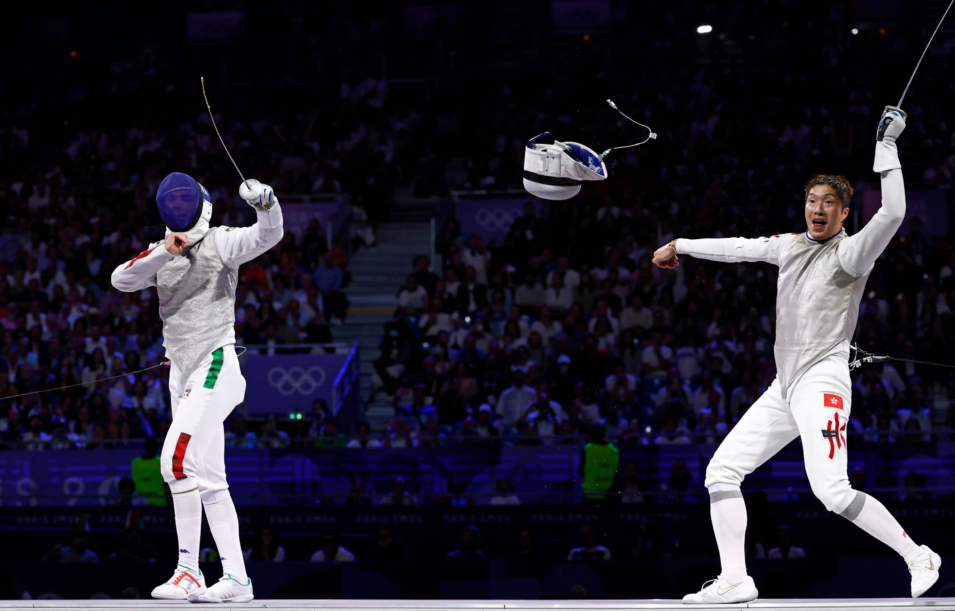 epa11507530 Ka Long Cheung (R) of Hong Kong celebrates after his beating Filippo Macchi (L) of Italy during Men Foil Individual Gold madal bout in the Fencing competitions in the Paris 2024 Olympic Games, at the Grand Palais in Paris, France, 29 July 2024.  EPA/YOAN VALAT