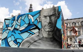 TOPSHOT - A painting of Real Madrid's French coach and former footballer Zinedine Zidane is pictured as an artist paints famous football players for an exhibition in front of the Hotel de Ville city hall in Paris on June 7, 2016, ahead of the start of the Euro 2016 football tournament.  / AFP / KENZO TRIBOUILLARD / RESTRICTED TO EDITORIAL USE - TO ILLUSTRATE THE EVENT AS SPECIFIED IN THE CAPTION        (Photo credit should read KENZO TRIBOUILLARD/AFP via Getty Images)