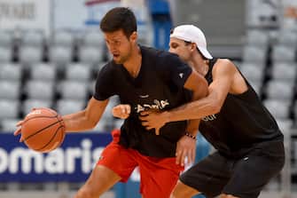This photograph taken on June 18, 2020, shows Serbia's Novak Djokovic (L) and Bulgaria's Grigor Dimitrov, tennis players, as they take part in an exhibition basketball match in Zadar. - Croatia's Borna Coric announced on June 22, 2020, that he has become the second player to test positive for coronavirus after taking part in an exhibition tournament in Croatia featuring world number one Novak Djokovic. "Hi everyone, I wanted to inform you all that I tested positive for COVID-19," the Croatian, ranked 33rd in the world, posted on Twitter. It follows the June 21, announcement by Grigor Dimitrov that he had also tested positive after pulling out of the exhibition event, which is one of the biggest since the tennis season was halted because of the pandemic. (Photo by STRINGER / AFP) / Croatia OUT (Photo by STRINGER/AFP via Getty Images)