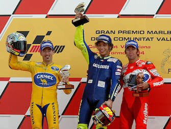 51630594 VALENCIA, SPAIN: Italian Valentino Rossi (C) Italian Max Biaggi (L) and Australian Troy Bayliss (R) pose on the podium of the Spanish Motorcycle Grand Prix at the Ricardo Tormo racetrack in Valencia, 31 October, 2004. AFP PHOTO/ JOSE JORDAN (Photo credit should read JOSE JORDAN/AFP via Getty Images)