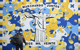 A pedestrian walks past a graffiti mural depicting Leeds United's Argentinian head coach Marcelo Bielsa as Christ the Redeemer, in Leeds, northern England on August 16, 2020. - Leeds United were promoted to the English Premier League last month after West Bromwich Albion's 2-1 defeat at Huddersfield ensured the Championship leaders ended their 16-year exile from the top-flight. (Photo by Oli SCARFF / AFP) (Photo by OLI SCARFF/AFP via Getty Images)