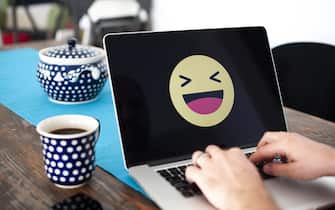A laptop with a happy emoji face displayed is seen in this photo illustration on October 15, 2018 in Warsaw, Poland. (Photo by Jaap Arriens/NurPhoto via Getty Images)