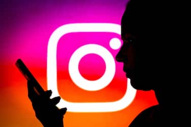 BRAZIL - 2022/03/14: In this photo illustration the Instagram logo seen in the background of a silhouette woman holding a mobile phone. (Photo Illustration by Rafael Henrique/SOPA Images/LightRocket via Getty Images)