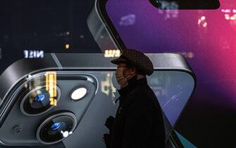 epa09629346 A person walks next to an Apple's iPhone advertisement at the Sanlitun shopping and residential area in Beijing, China, 08 December 2021.  EPA/ROMAN PILIPEY