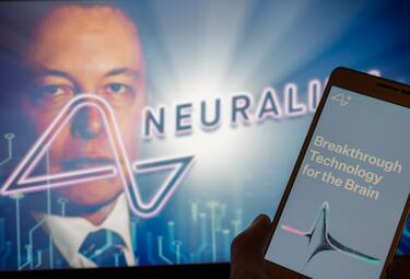Neuralink logo displayed on mobil with founder Elon Musk seen on screen in the background. Neuralink Corporation is a neurotechnology company that develops implantable brain-computer interfaces. In Brussels on 4 December 2022. (Photo Illustration by Jonathan Raa/NurPhoto via Getty Images)
